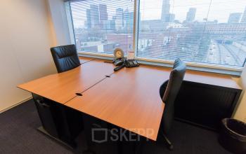 Kantoorruimte huren aan Jan Pietersz. Coenstraat 7 in Den Haag Haagse Hout met een prachtig uitzicht op de skyline van de stad, voorzien van twee bureaus en stoelen.