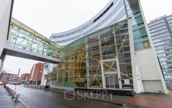 Moderne gevel van een kantoorpand aan de Jan Pietersz. Coenstraat 7 in Den Haag Haagse Hout, met grote glaspartijen en een overdekte entree.