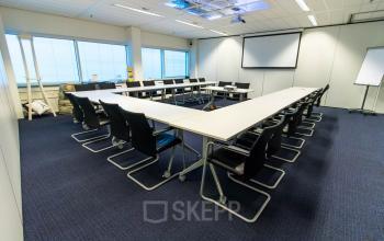 Moderne vergaderruimte binnen het kantoorpand op Jan Pietersz. Coenstraat 7, Den Haag Haagse Hout, met een lange tafel en stoelen.