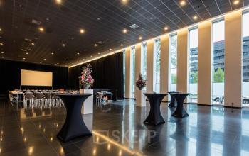 Moderne, ruime kantoorruimte met hoge ramen en chique inrichting op Prinses Margrietplantsoen 25, Den Haag Haagse Hout. Tafels en stoelen in conferentie-opstelling, ideaal om te huren voor zakelijke evenementen.