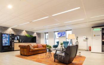 Gezellige lounge in het kantoorpand aan Prinses Margrietplantsoen 25, Den Haag Haagse Hout. Comfortabele zitplaatsen met een warme sfeer voor ontspannen bijeenkomsten. Ideale plek voor kantoorruimte huren.