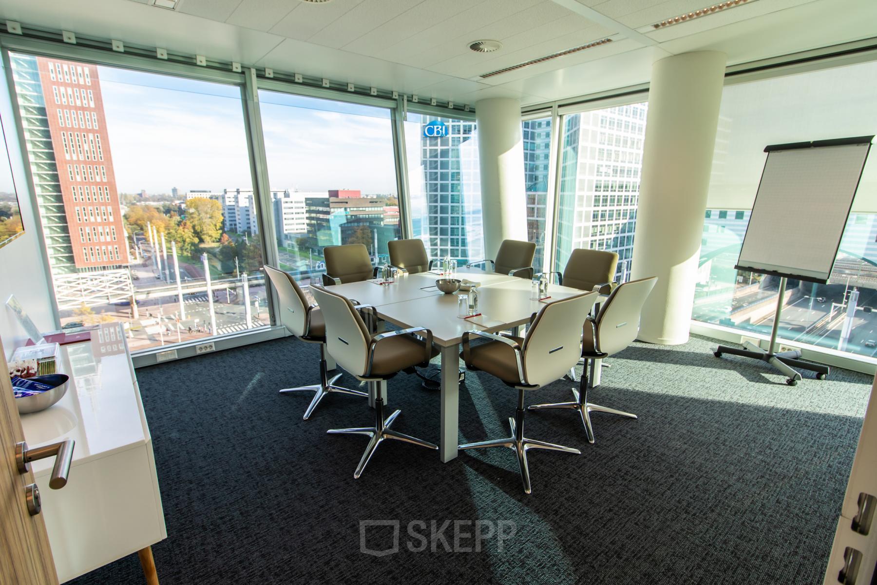 Moderne, lichte vergaderruimte in Den Haag met uitzicht op het stadscentrum. Kantoorruimte huren met glazen wanden en comfortabele stoelen rondom een vergadertafel. Perfect voor zakelijke bijeenkomsten.