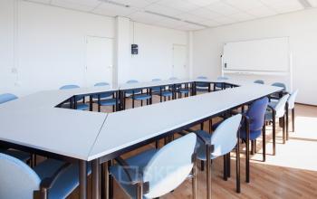 Verlichte vergaderruimte in kantoorpand Calandstraat 1 - 35, Den Haag Laak, met U-vormige tafelopstelling en blauwe stoelen, ideaal voor bedrijven die kantoorruimte huren voor bijeenkomsten en conferenties.