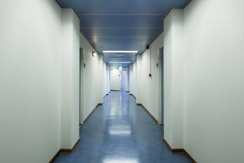 Heldere gang in kantoorpand Calandstraat 1-35 in Den Haag Laak, met blauw tapijt en toegangsdeuren naar kantoorruimtes.