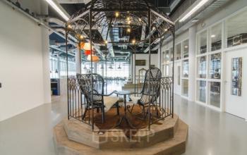 Modern ingerichte kantoorruimte met unieke vergaderruimte in een stijlvolle kooi-achtige structuur, gevestigd in het kantoorpand aan Oude Middenweg 3-19 in Den Haag.