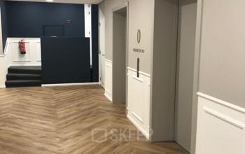 Een moderne, goed verlichte kantoorruimte met houten vloer, twee liften en een trap aan de Johan de Wittlaan 3-7, Den Haag Statenkwartier, ideaal voor kantoren te huur.