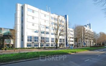 Exterieur van een modern kantoorpand aan Johan de Wittlaan 7, Den Haag Statenkwartier, met strakke gevels en omliggende bomen. Ideale locatie voor het huren van kantoorruimte.