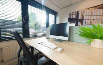 Kantoorruimte huren aan de Keulenstraat 9 in Deventer met een modern ingerichte werkplek, voorzien van een bureau met beeldscherm, toetsenbord en stoel, omgeven door groene accenten en grote ramen die veel licht binnenlaten.