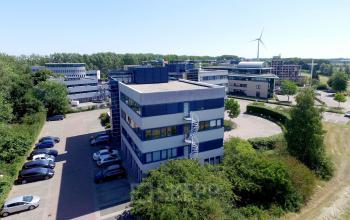 Exterieur van het kantoorpand op Keulenstraat 15, Deventer, omringd door bomen en parkeerplaatsen. Geschikt voor bedrijven die kantoorruimte willen huren in een groene omgeving.
