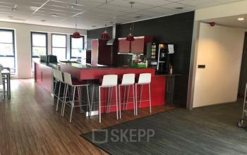 Kantoorruimte huren op Keulenstraat 15 in Deventer met een moderne pantry met rode accenten, hoge krukken en veel natuurlijk licht.