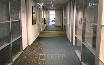 Kantoorruimte gereserveerd op Keulenstraat 15 in Deventer met lange gang en glazen wanden langs de kantoren. Ideaal voor zakelijke interacties en flexibele huurmogelijkheden in een professioneel kantoorpand.