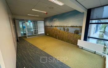Ruime kantoorruimte op Keulenstraat 15, Deventer met veel natuurlijk licht en een rustgevend uitzicht op een muurschildering van een landschap. Ideaal voor bedrijven die kantoorruimte huren willen overwegen.
