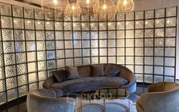 Gezellige loungehoek in kantoorpand aan de Keulenstraat 1, Deventer met stijlvolle zitplaatsen en moderne glasstenen muur, ideaal om kantoorruimte te huren en te ontspannen.
