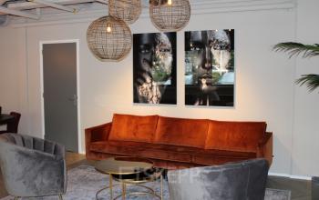 Sfeervolle lounge in kantoorpand op Keulenstraat 1, Deventer, met comfortabele banken en moderne kunstwerken aan de wand; ideaal voor huur.