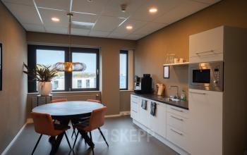 Kantoorruimte met een moderne kitchenette en een ronde tafel met stoelen, ideaal voor een pauze of informeel overleg. Gelegen op Keulenstraat 1 in Deventer, perfect om te huren voor jouw bedrijf.