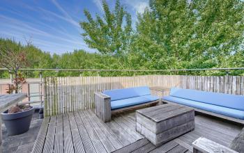 Moderne kantoorpand buitenruimte met houten vloerdek, comfortabele buitenbanken en groene bomen bij Wisselwerking 40-48 in Diemen.