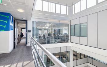 Lichte en moderne kantoorruimte op Wisselwerking 40-48, Diemen, met een open vloerplan en veel ramen. Personen voeren zakelijke gesprekken terwijl ze door het gebouw lopen.