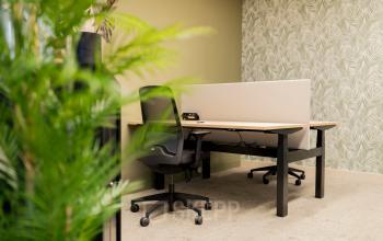 Kantoorruimte huren op Diemerhof 42 in Diemen, met een werkplek voorzien van bureau en stoel, tegen een stijlvolle groene wand.