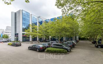 Modern kantoorpand aan Diemermere 11-19 in Diemen, omgeven door bomen met ruime parkeerplaatsen voor het gebouw, ideaal voor kantoorruimte huren.