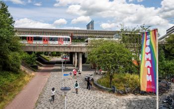 Exterieur van het kantoorpand aan Diemermere 11-19 in Diemen, met mensen die passeren en uitzicht op de tramrails.