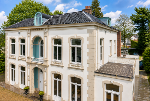 Gevel van een statig kantoorpand aan de Dorpsstraat 77 in Doorn met klassieke details en grote ramen, ideaal voor het huren van een kantoorruimte.