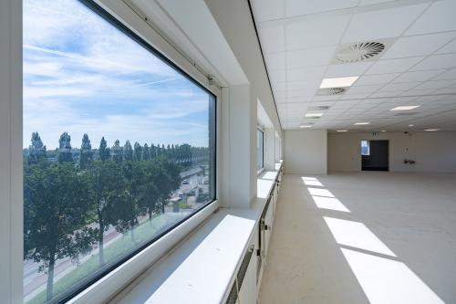 Ruime, lichtrijke kantoorruimte te huur op Mijlweg 61, Dordrecht, met grote ramen en uitzicht op een groen landschap. Ideaal voor open werkplekken binnen een modern kantoorpand.