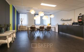 Gezellige open ruimte in het kantoorpand aan Van Knobelsdorffplein 14, Drachten, met moderne lampen boven een tafel en keukenfaciliteiten, ideaal voor kantoorruimte huren.