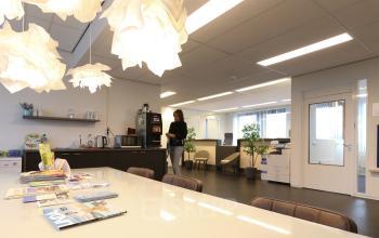 Interieur van een modern kantoorpand op Van Knobelsdorffplein 14, Drachten, met comfortabele zithoek, lichtinval en persoon bezig met zakelijke activiteit. Mogelijkheid om kantoorruimte te huren.
