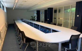 Moderne vergaderruimte in kantoorpand aan de Galvanistraat 1 in Ede, met een grote witte tafel en comfortabele stoelen.