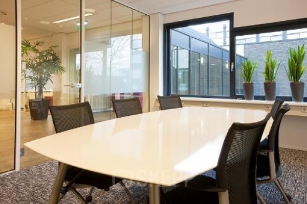 Modern ingerichte vergaderruimte binnen kantoorpand aan Galvanistraat 1, Ede met een lange tafel, comfortabele stoelen en veel natuurlijk licht.