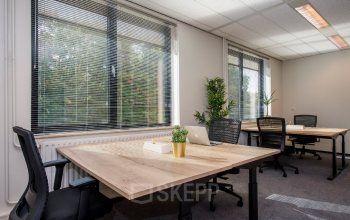 Verlichte kantoorruimte op Galvanistraat 7, Ede met drie houten bureaus, ergonomische bureaustoelen en laptops, omringd door grote ramen met horizontale jaloezieën en veel natuurlijk licht.