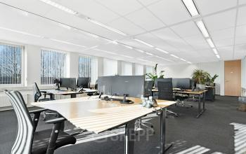 Heldere kantoorruimte in Ede op Celsiusstraat 34, met moderne bureaus en stoelen bij grote ramen. Ideaal voor wie een kantorenpand wil huren.