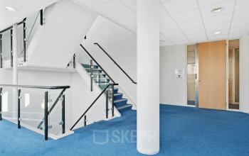 Kantoorpand aan de Celsiusstraat 34 in Ede met een moderne trap en blauwe vloerbedekking, ideaal voor kantoorruimte huren.