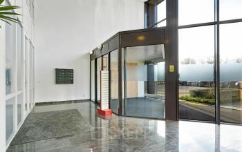 Entree van een kantoorpand op Celsiusstraat 34, Ede, met glazen deuren en marmeren vloer, ideaal voor wie een professionele kantoorruimte wil huren.
