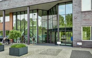 Buitenzijde van een modern kantoorpand op Celsiusstraat 34 in Ede, met glazen entree en parkeerplaatsen. Ideaal voor kantoorruimte huren.
