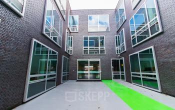 Buitenzijde van een kantoorpand op Flight Forum 40, Eindhoven Airport, met moderne architectuur en grote raampartijen rondom een open ruimte.
