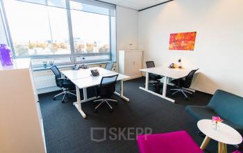 Moderne kantoorruimte huren op Flight Forum 40 in Eindhoven Airport met drie bureaus, stoelen en kleurrijke decoratie bij het raam.