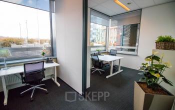 Kantoorruimte huren op Flight Forum 40 in Eindhoven Airport met moderne meubels en veel daglicht. Twee werkplekken zijn ingericht met bureaus en stoelen. Planten zorgen voor een aangename sfeer.