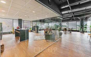 Moderne kantoorruimte huren op Eindhoven Airport met glazen wanden en houten vloeren, voorzien van stijlvolle meubels. De lichte omgeving zorgt voor een inspirerende werkplek nabij Flight Forum 760-780.