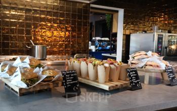 Binnenkant van het kantoorpand op Flight Forum 760-780, Eindhoven Airport, met een uitnodigende pantry waar smakelijke broodjes en snacks uitgestald zijn voor de huurders.