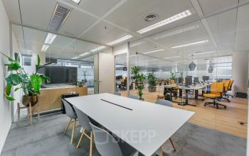Moderne kantoorruimte op Eindhoven Airport met glazen wanden, vergadertafel, en zicht op open kantoorlandschap. Geschikt voor bedrijven die kantoorruimte willen huren op Flight Forum 760-780.