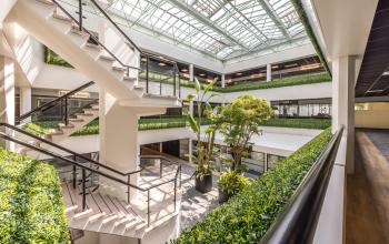 Ruim atrium van het kantoorpand op Luchthavenweg 81, Eindhoven Airport, met veel groen en open trappenhuis. Ideaal voor kantoorruimte huren met een moderne uitstraling.