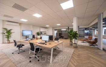 Ruime en moderne kantoorruimte met open werkplekken en comfortabele stoelen bij Eindhoven Airport, perfect voor wie op zoek is naar kantoorruimte huren. Strakke inrichting en veel natuurlijk licht.