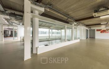 Moderne kantoorruimte te huur op Luchthavenweg 81, Eindhoven Airport, met een open vloerplan en industriële elementen.