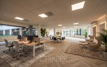Ruime kantoorruimte met moderne werkplekken, comfortabele stoelen en grote ramen, ideaal voor kantoorruimte huren bij Eindhoven Airport.