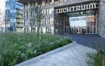 Buitenzicht op het moderne kantoorpand Flight Forum 120-159 in Eindhoven Airport, omringd door groen. Deze locatie biedt diverse mogelijkheden voor kantoorruimte huren.
