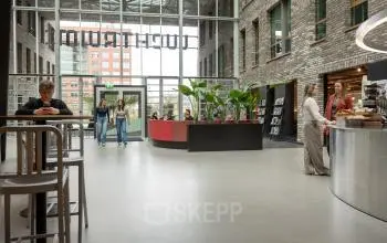 Moderne en lichte kantoorruimte op Flight Forum 120-159, Eindhoven Airport. Mensen wisselen ideeën uit bij het koffiepunt. Perfecte plek voor je volgende kantoor om te huren.