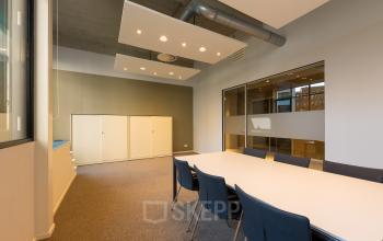 Moderne kantoorruimte te huur in Eindhoven Centrum, Lichttoren 32, met vergadertafel en stoelen, veel lichtinval door grote ramen, ideaal voor vergaderingen en brainstormsessies.