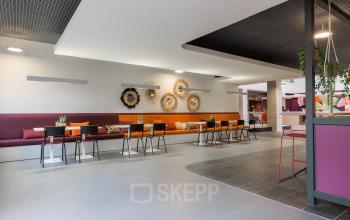 Een moderne, kleurrijke werkruimte in een kantoorpand aan Stadhuisplein 10, Eindhoven Centrum, met stijlvolle zitplaatsen en decoratieve elementen. Perfect om kantoorruimte te huren voor creatieve zakelijke activiteiten.