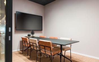 Vergaderruimte in kantoorpand met strakke inrichting, inclusief tafel met zes stoelen en een groot scherm aan de muur, gelegen op Stadhuisplein 10, Eindhoven Centrum. Kantoorruimte huren mogelijk.